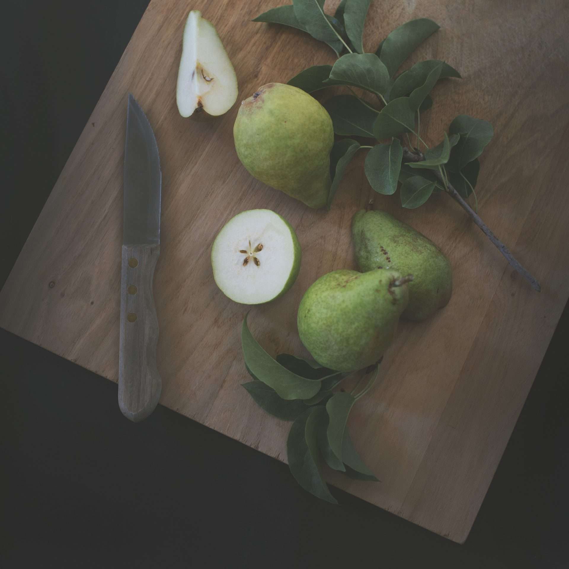 Green pears but in half on a brown cutting board