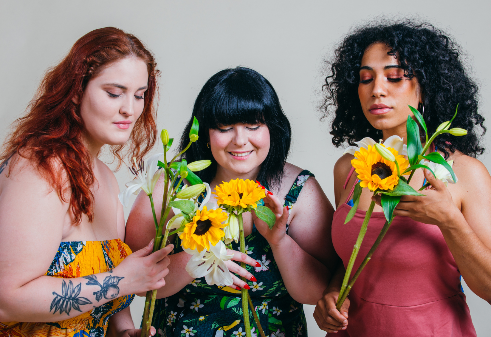 Three women holding and smelling sunflowers